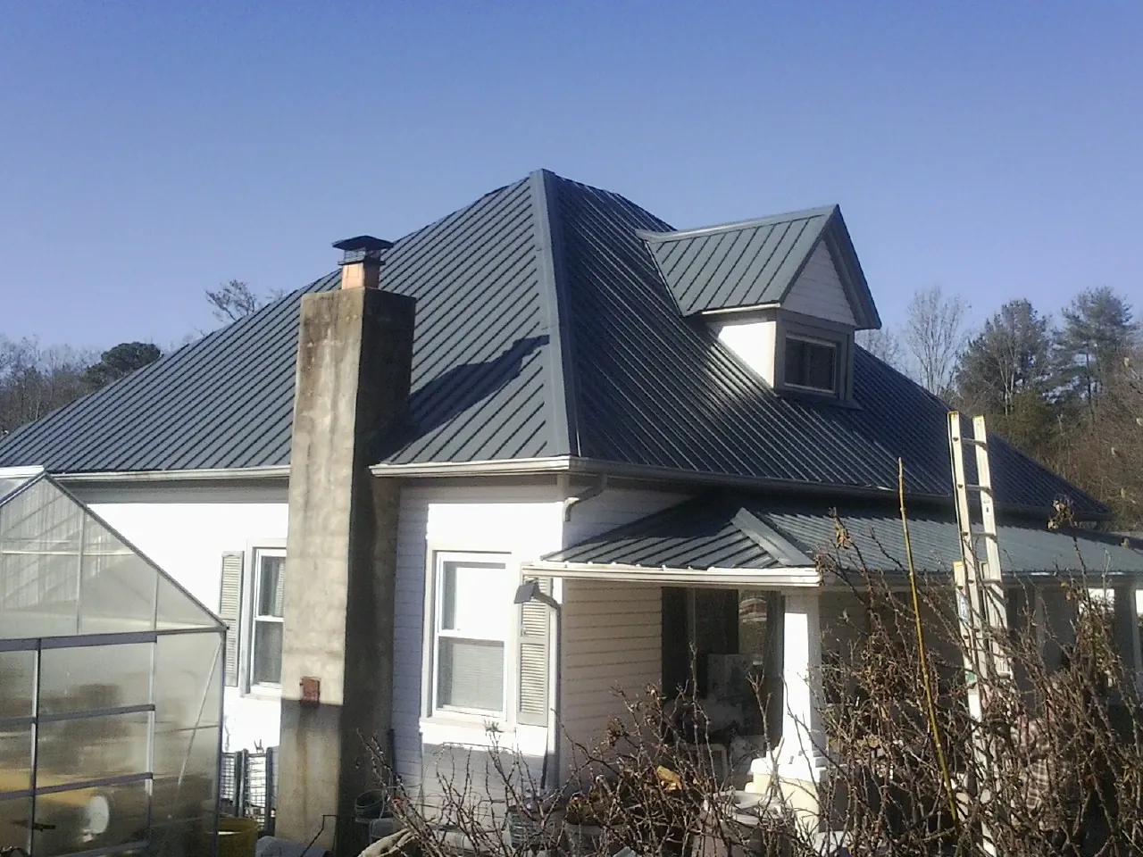 Dark blue standing seam metal roof on a white farmhouse with dormer — Slate & Tile Roof Repair by Roofing Brothers in Bullhead City