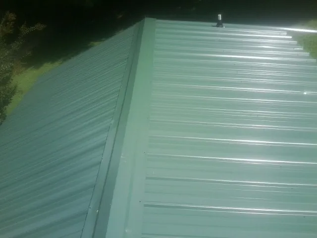 New green metal panels meeting at the ridge of a roof — Flat Roof Repair work by our crew in Bullhead City