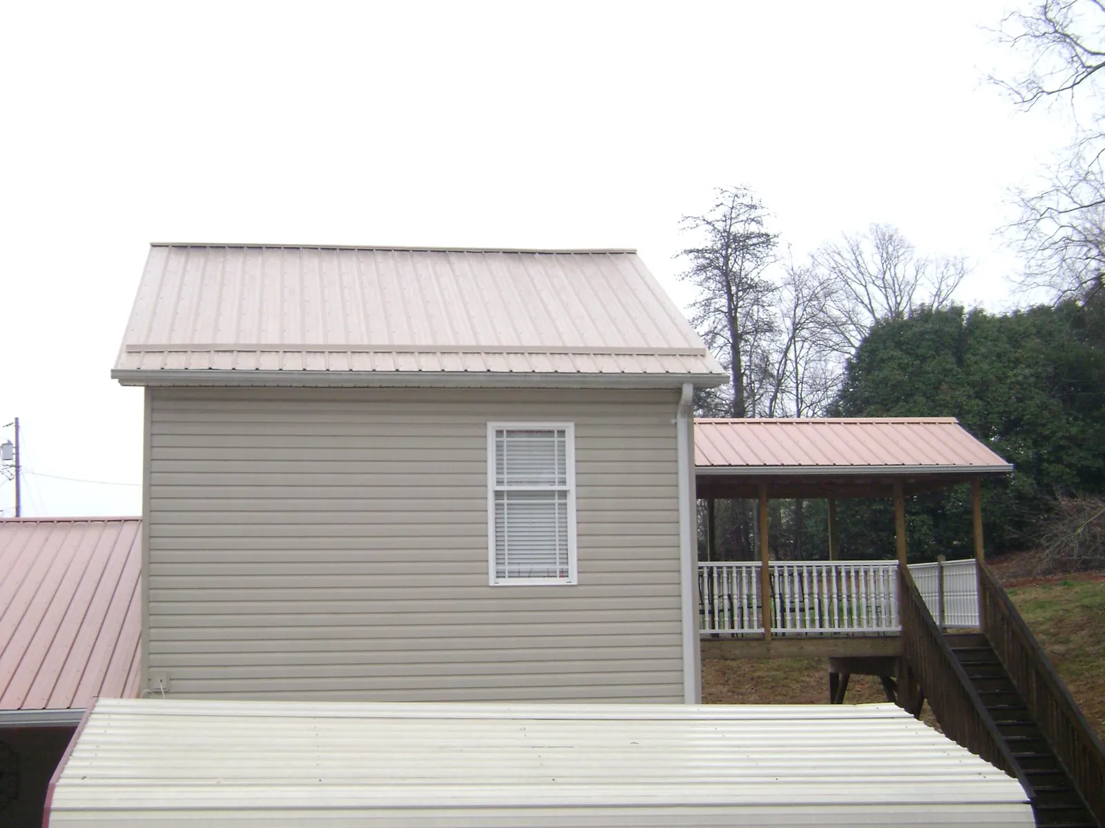 Tan metal roofs on a two story addition and attached porch, from a Roof Replacement job in Bullhead City