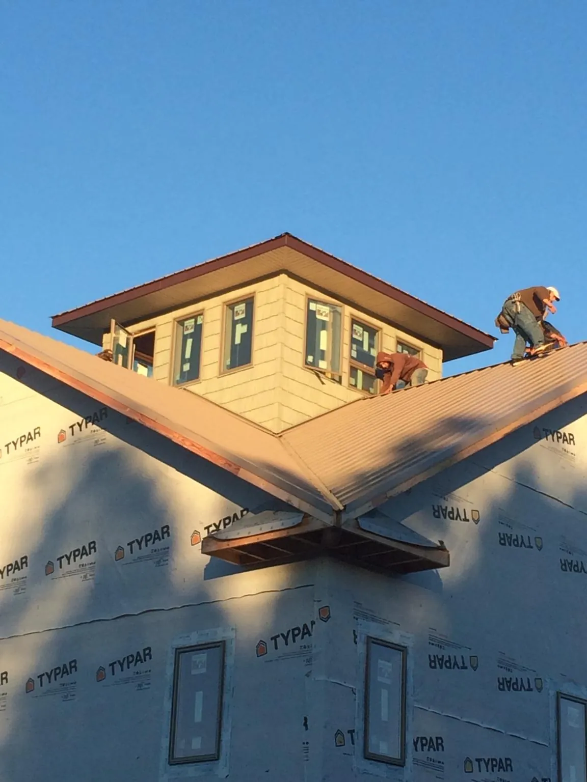 Roofers working around a rooftop cupola on a new metal roof at sunset — Roof Waterproofing in Bullhead City by Roofing Brothers